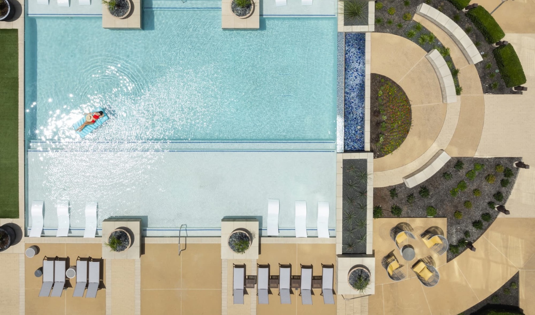 HOME + HOSPITALITY pool with modern stonework and reclining seats